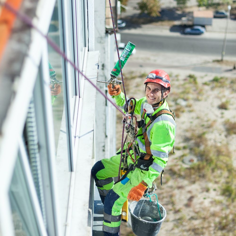 Industrial climber on building during winterization works, looking up at camera and smiling Industrial climber on building during winterization works, looking up at camera and smiling